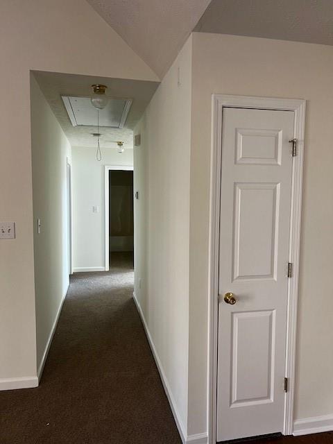 corridor with vaulted ceiling and dark carpet