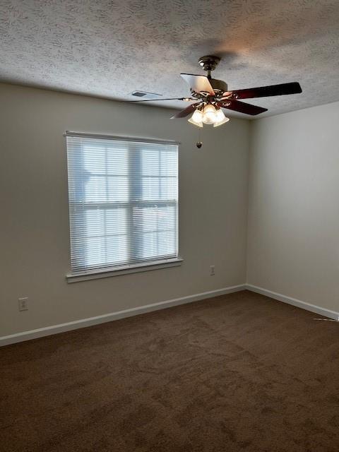 spare room featuring ceiling fan, a textured ceiling, and dark colored carpet