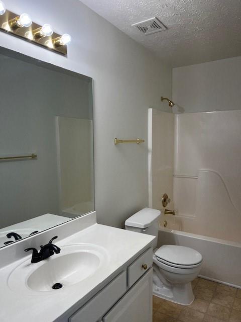 full bathroom featuring toilet, vanity, a textured ceiling, and bathtub / shower combination