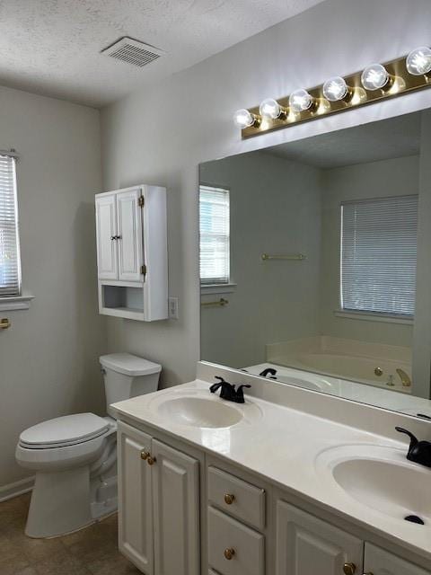 bathroom featuring vanity, a bath, toilet, and a textured ceiling