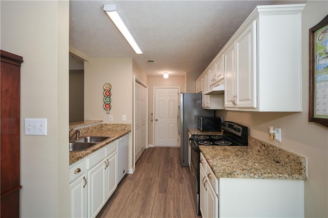 kitchen with white cabinets, sink, hardwood / wood-style flooring, light stone counters, and stainless steel appliances