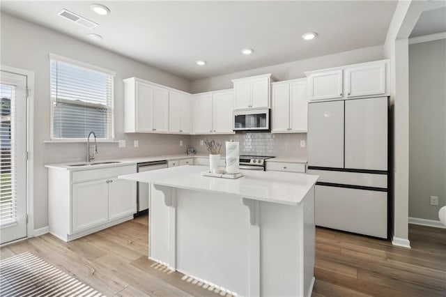 4172 Cedar Commons Way, Conley, GA 30288 - kitchen with stainless steel appliances, a sink, a kitchen island, backsplash, and white cabinetry