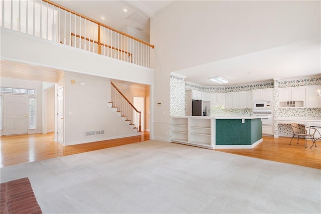 unfurnished living room featuring high vaulted ceiling and light hardwood / wood-style floors