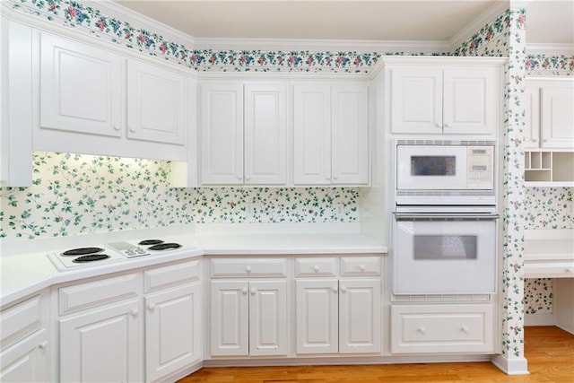 kitchen featuring crown molding, white cabinets, and white appliances