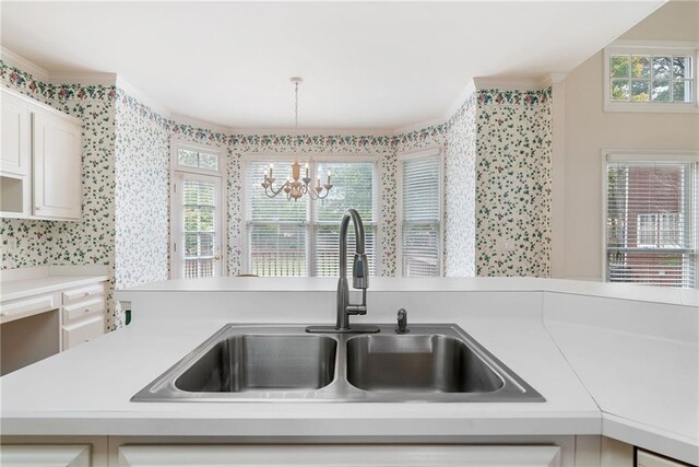 kitchen with sink, white cabinets, a chandelier, and decorative light fixtures