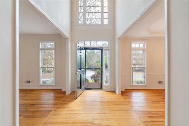 entryway with crown molding and light hardwood / wood-style floors