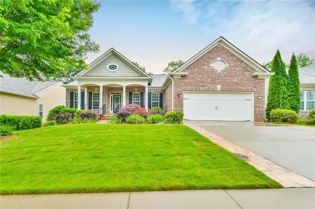 6714 Amherst Dr, Hoschton, GA 30548 - neoclassical home featuring concrete driveway, brick siding, covered porch, a front lawn, and a garage