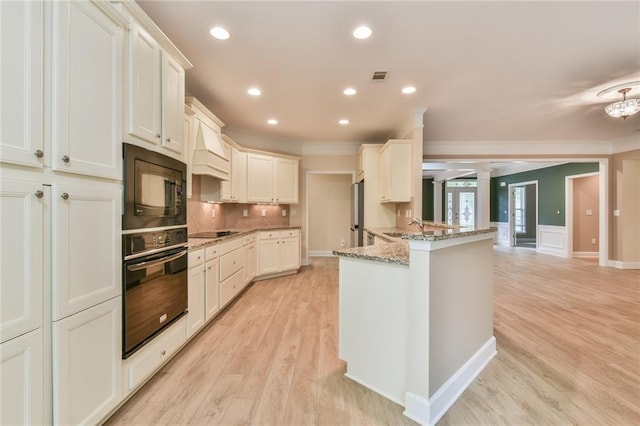 6714 Amherst Dr, Hoschton, GA 30548 - kitchen featuring black appliances, ornamental molding, light stone counters, light wood-style floors, and a sink
