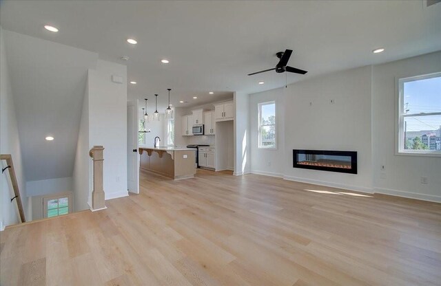1915 Deco Dr, Kennesaw, GA 30144 - unfurnished living room with light wood finished floors, a glass covered fireplace, a ceiling fan, and recessed lighting