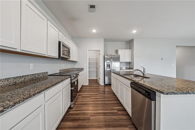 31 Mccall Way, Monroe, GA 30655 - kitchen with stainless steel appliances, dark wood finished floors, white cabinetry, a center island with sink, and recessed lighting