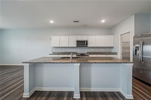 31 Mccall Way, Monroe, GA 30655 - kitchen with stainless steel appliances, dark wood finished floors, dark stone counters, a kitchen island with sink, and white cabinets