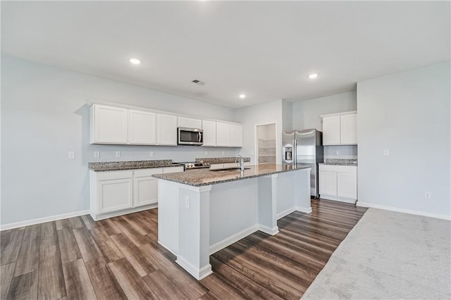 31 Mccall Way, Monroe, GA 30655 - kitchen featuring stainless steel appliances, dark wood-style floors, dark stone counters, a center island with sink, and white cabinets