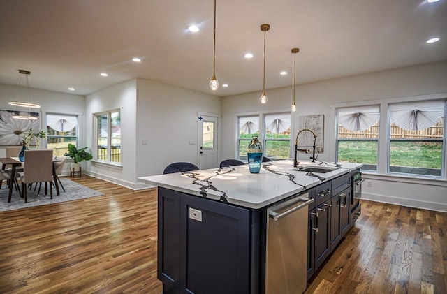 kitchen with a kitchen island with sink, sink, decorative light fixtures, and dark hardwood / wood-style flooring