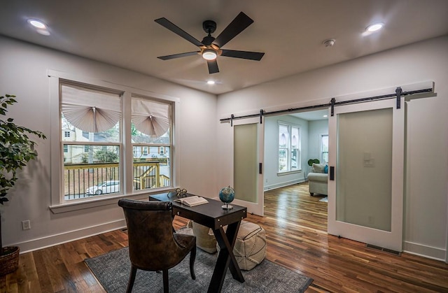 office space with dark hardwood / wood-style floors, ceiling fan, and a barn door