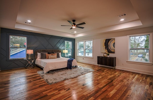 bedroom featuring dark wood-type flooring, ceiling fan, and a tray ceiling