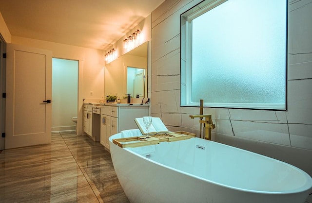 bathroom featuring vanity, a washtub, and toilet