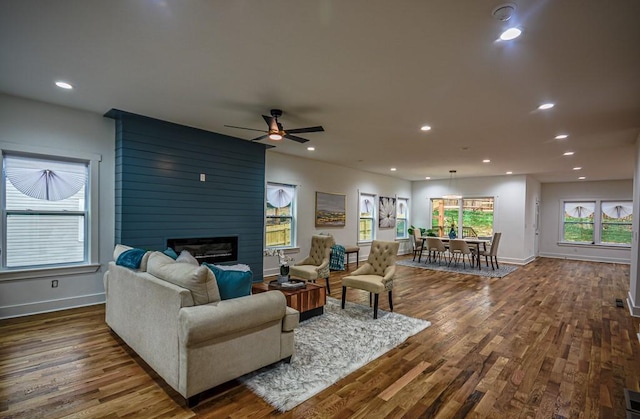 living room with dark hardwood / wood-style floors, a large fireplace, and ceiling fan