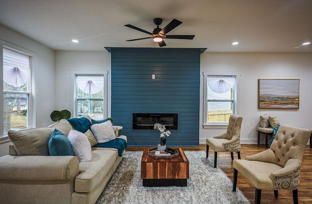 living room with wood-type flooring, a large fireplace, and ceiling fan