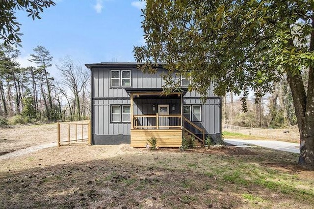 view of front facade with board and batten siding, fence, and dirt driveway