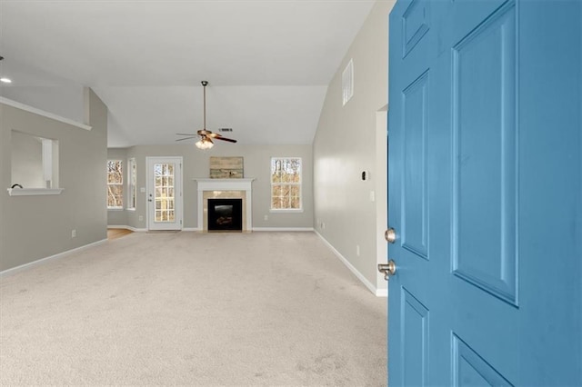 unfurnished living room with ceiling fan, vaulted ceiling, light carpet, and a wealth of natural light