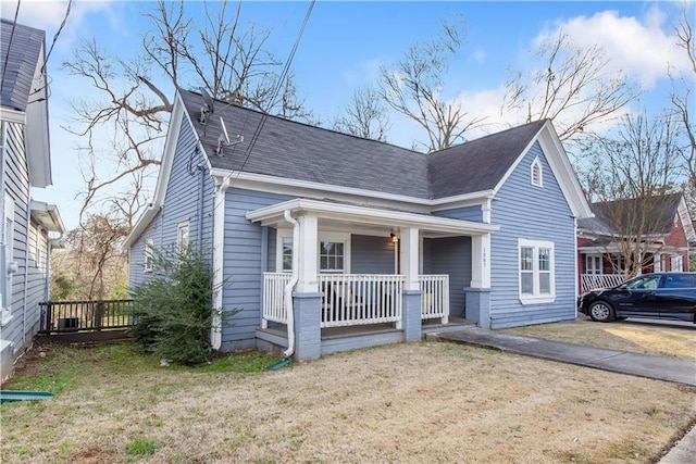 bungalow-style house with roof with shingles, a porch, and a front lawn