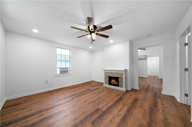 unfurnished living room with dark wood-type flooring, a stone fireplace, cooling unit, and ceiling fan