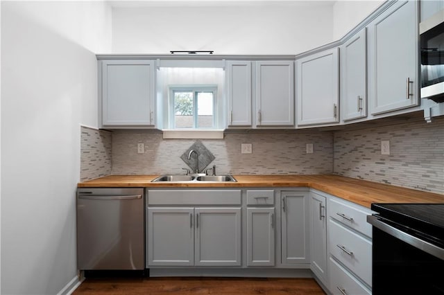 kitchen with stainless steel appliances, sink, dark hardwood / wood-style floors, backsplash, and butcher block countertops