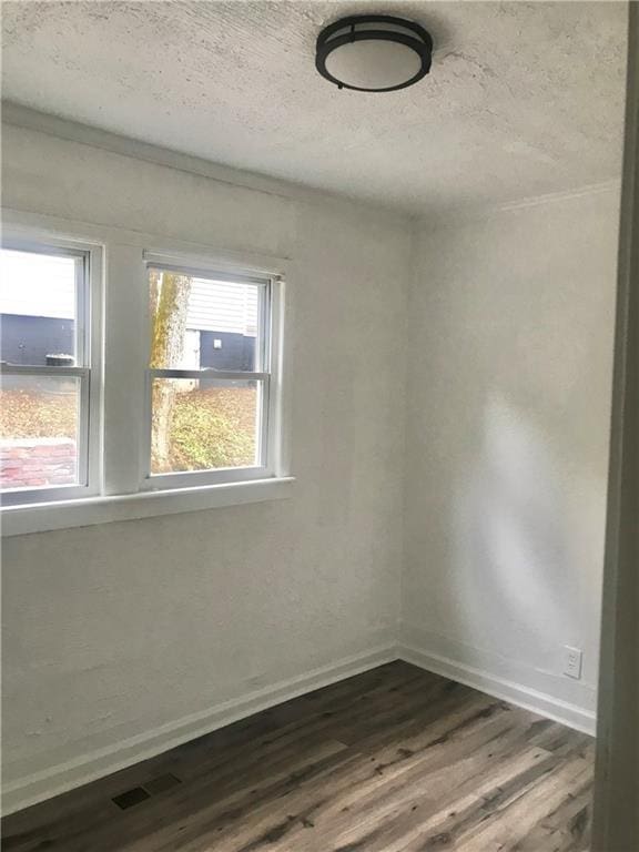 empty room with a textured ceiling and hardwood / wood-style floors