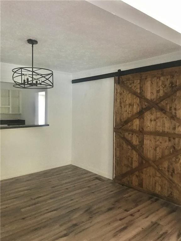 empty room with a barn door, a textured ceiling, and hardwood / wood-style flooring