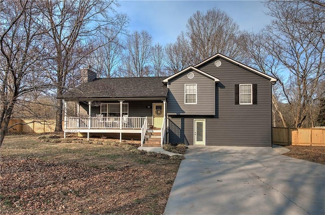 split level home with a chimney, a porch, a shingled roof, fence, and driveway