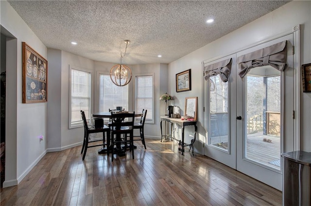 dining area featuring a textured ceiling, a chandelier, wood finished floors, and french doors