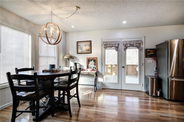 dining space with french doors, recessed lighting, a textured ceiling, wood finished floors, and a chandelier