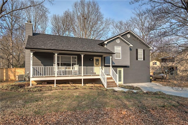 tri-level home with central AC unit, a chimney, roof with shingles, fence, and a porch