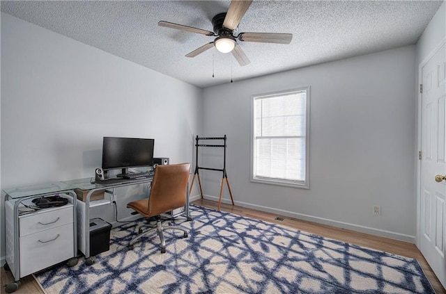 home office featuring a ceiling fan, a textured ceiling, baseboards, and wood finished floors