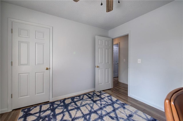 bedroom with dark wood-style floors, ceiling fan, a textured ceiling, and baseboards