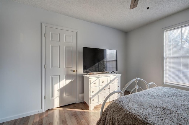 bedroom featuring a textured ceiling, ceiling fan, wood finished floors, and baseboards