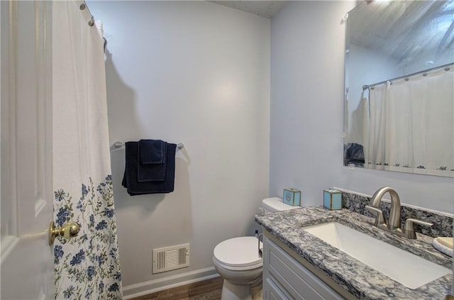 bathroom with toilet, wood finished floors, vanity, visible vents, and baseboards