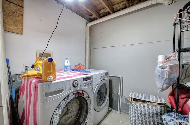 clothes washing area with a garage, laundry area, and washer and clothes dryer