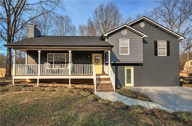 tri-level home with driveway, a porch, and a chimney