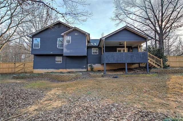 rear view of property featuring stairway, fence, and a ceiling fan