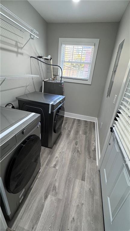 laundry area featuring separate washer and dryer, light hardwood / wood-style flooring, and water heater