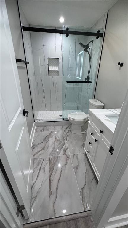 bathroom featuring a shower with door, vanity, and toilet