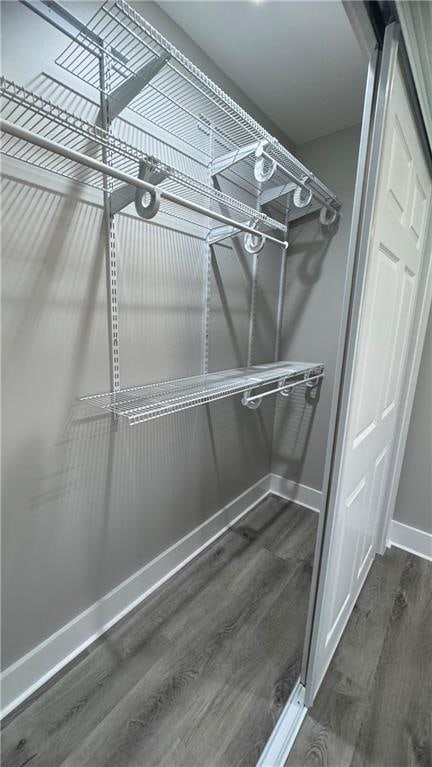 walk in closet with dark wood-type flooring