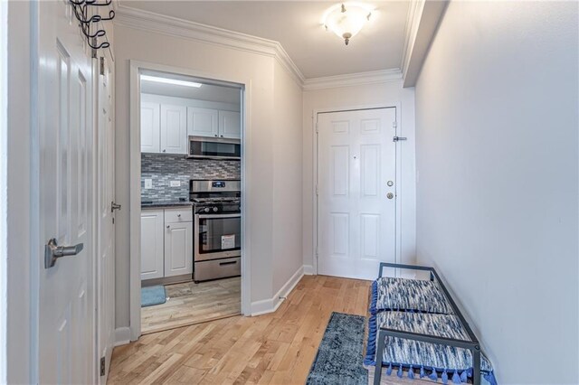 interior space featuring light wood-type flooring, crown molding, and baseboards