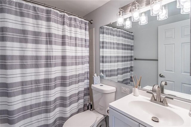 bathroom with curtained shower, toilet, and vanity