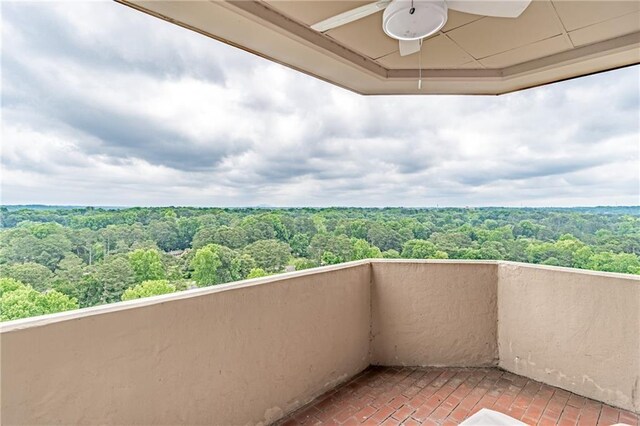 balcony featuring ceiling fan and a wooded view