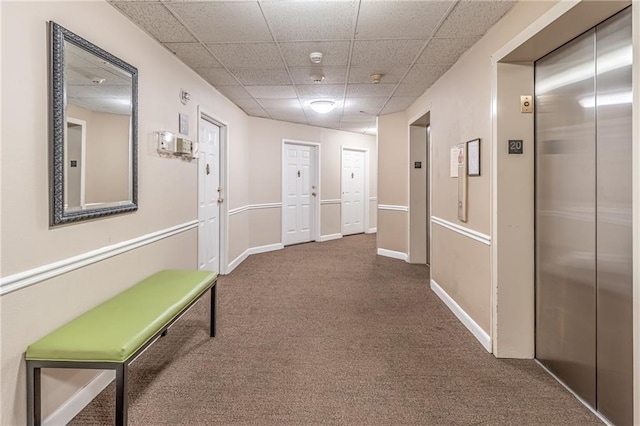 hallway featuring baseboards, a paneled ceiling, elevator, and carpet floors