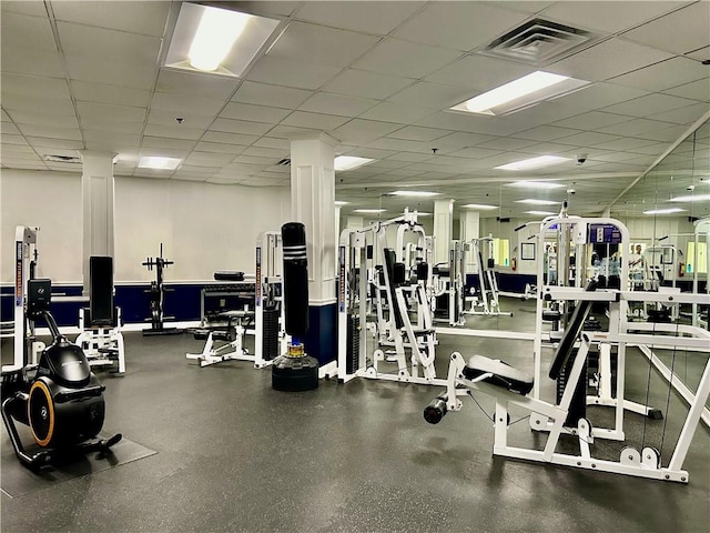 workout area with visible vents, a paneled ceiling, and decorative columns