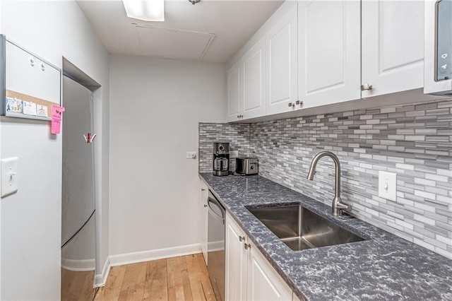 kitchen with a sink, decorative backsplash, white cabinets, stainless steel dishwasher, and light wood-type flooring