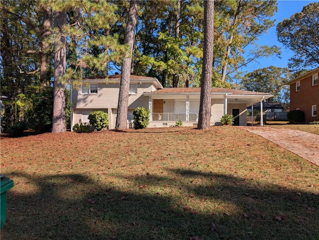 view of front of property featuring covered porch, a front yard, and a carport